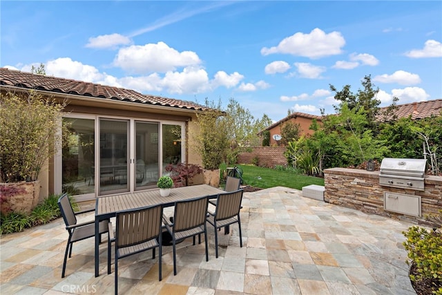 view of patio / terrace featuring outdoor dining space, fence, grilling area, and an outdoor kitchen
