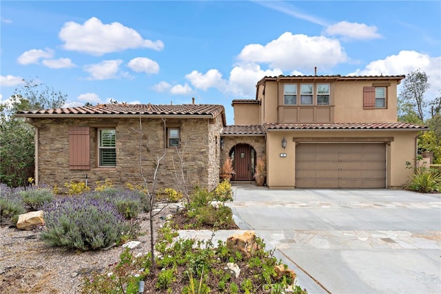 mediterranean / spanish house featuring a tile roof, concrete driveway, an attached garage, stone siding, and stucco siding