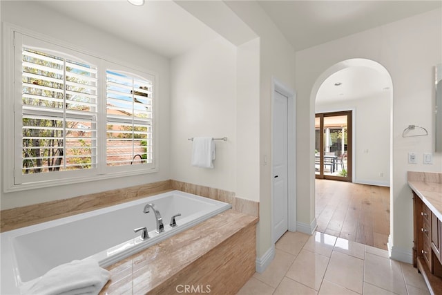 bathroom featuring vanity, tile patterned flooring, baseboards, and a bath