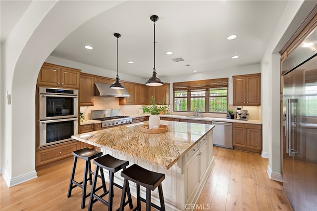 kitchen with a kitchen island, visible vents, appliances with stainless steel finishes, a sink, and under cabinet range hood