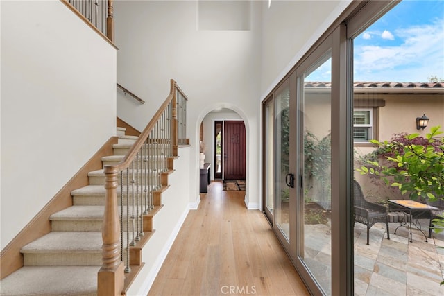 entrance foyer featuring arched walkways, wood finished floors, a wealth of natural light, and stairway