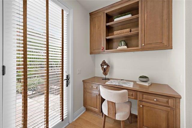 home office with built in study area and light wood-style floors