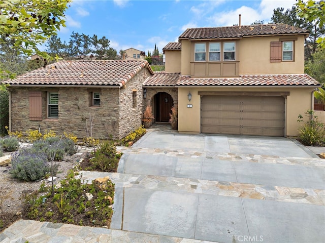 mediterranean / spanish-style house featuring stone siding, stucco siding, a tiled roof, concrete driveway, and an attached garage