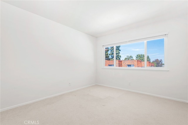 empty room featuring baseboards and light carpet