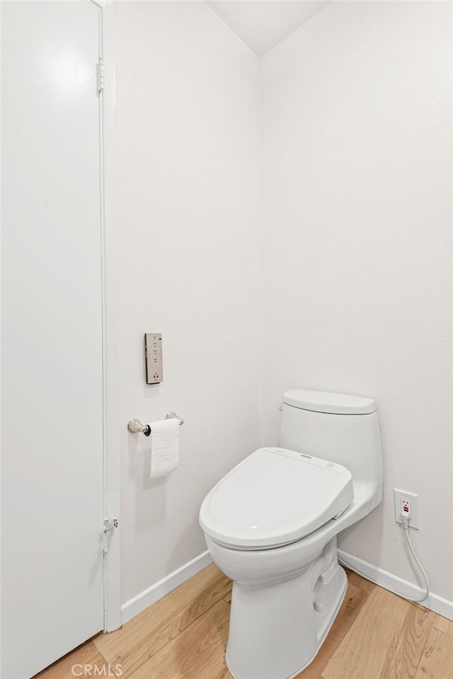bathroom with toilet, baseboards, and wood finished floors