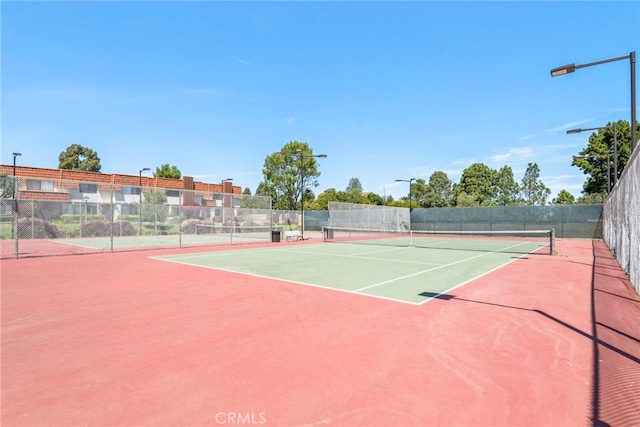 view of tennis court featuring fence and community basketball court