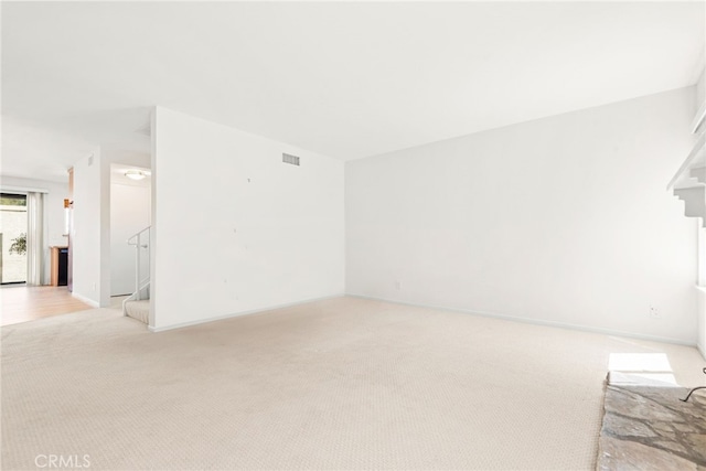 unfurnished living room with visible vents, stairs, baseboards, and light carpet