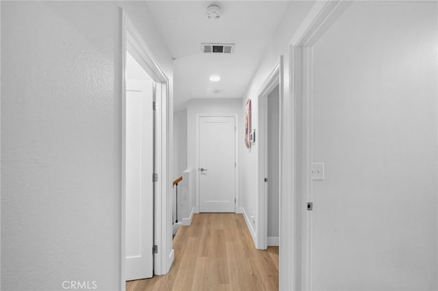 hall with baseboards, visible vents, and light wood-style floors