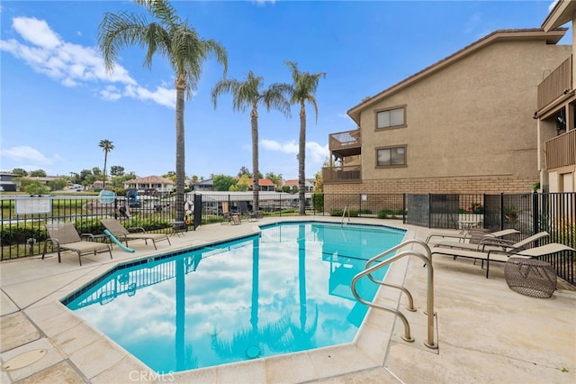 community pool with fence and a patio