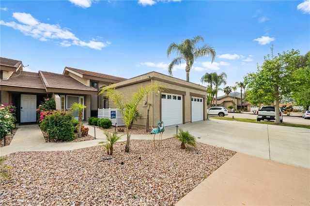 view of front of property with an attached garage, cooling unit, stucco siding, and concrete driveway