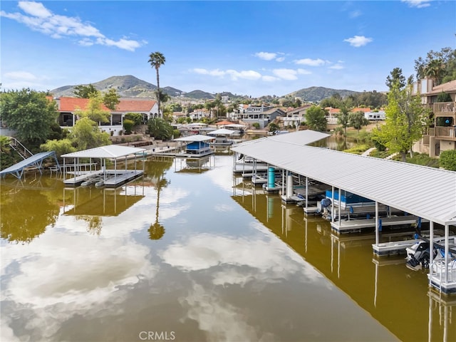 dock area featuring a water and mountain view, boat lift, and a residential view