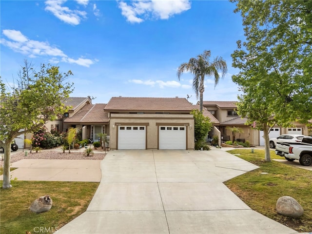 view of front of property with an attached garage, stucco siding, and a front yard