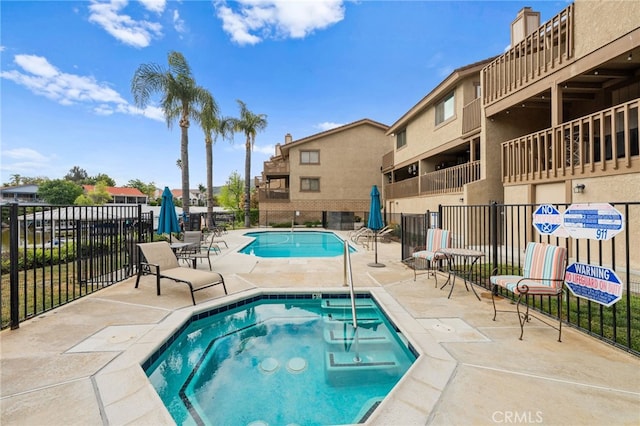 pool with a hot tub, fence, and a patio area