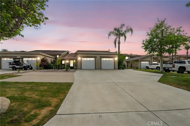 prairie-style house with concrete driveway, a lawn, an attached garage, and stucco siding