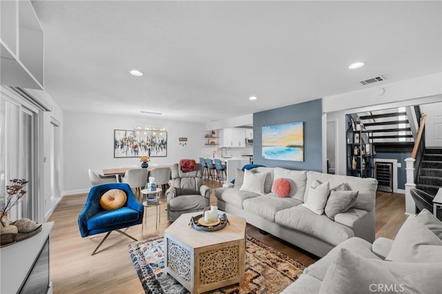 living room with a chandelier, recessed lighting, light wood-type flooring, visible vents, and stairway
