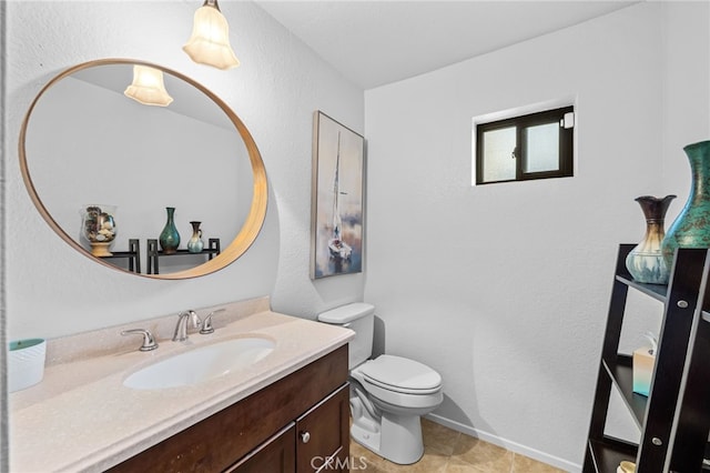half bath featuring vanity, baseboards, a textured wall, and toilet