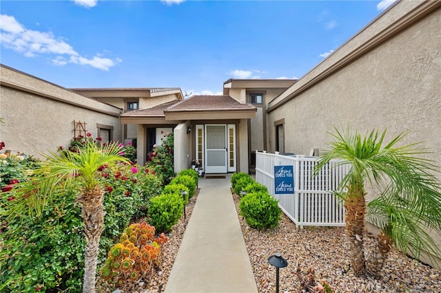 entrance to property with fence and stucco siding