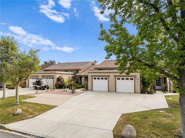 view of front of home featuring an attached garage, a front lawn, driveway, and stucco siding