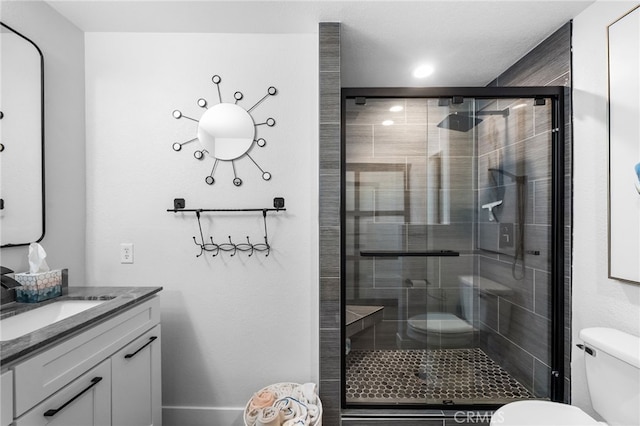 bathroom with vanity, a shower stall, and toilet