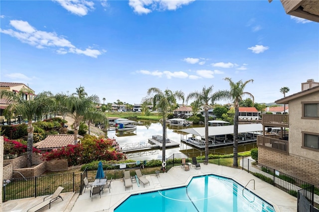 community pool with a patio, a water view, and fence