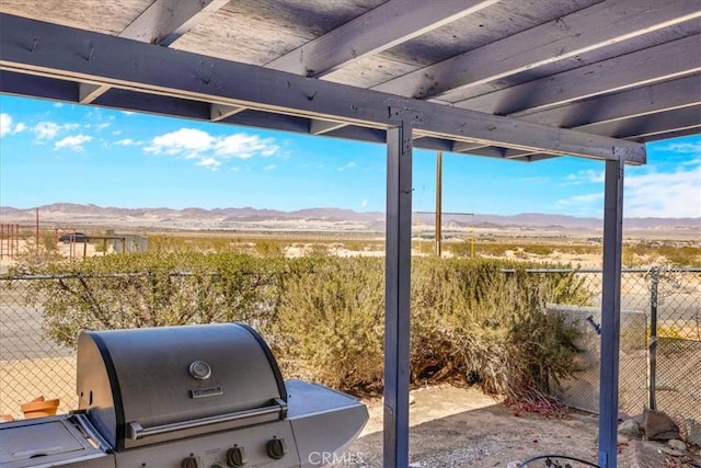 view of patio featuring a grill, a mountain view, and fence