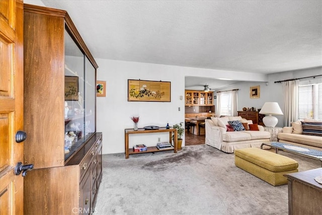 carpeted living room with a textured ceiling and ceiling fan