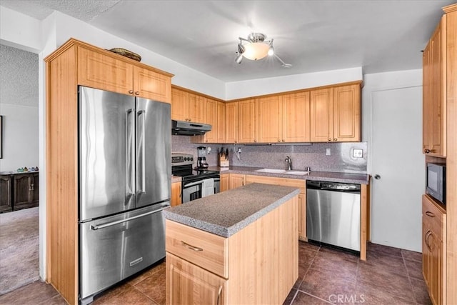 kitchen with under cabinet range hood, appliances with stainless steel finishes, a kitchen island, backsplash, and a sink