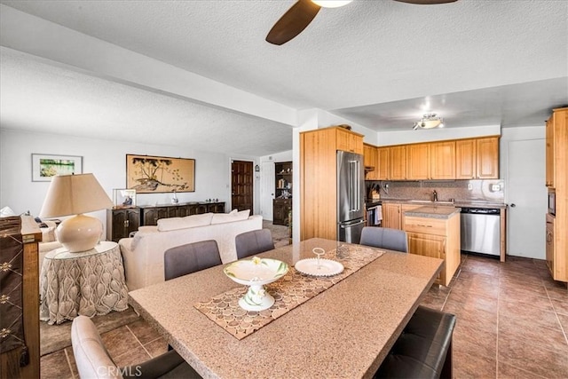 tiled dining room with a textured ceiling, a ceiling fan, and a sink