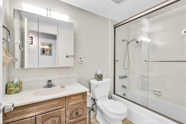 bathroom with toilet, vanity, and combined bath / shower with glass door