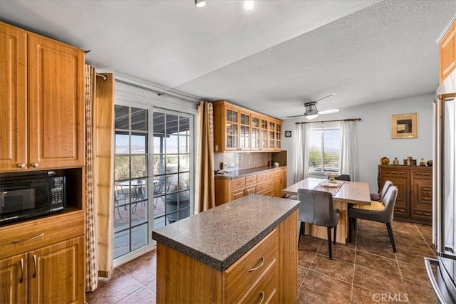 5304 Morongo Rd Unit 29, Palms, CA 92277 - kitchen with black microwave, dark countertops, a kitchen island, and dark tile patterned flooring