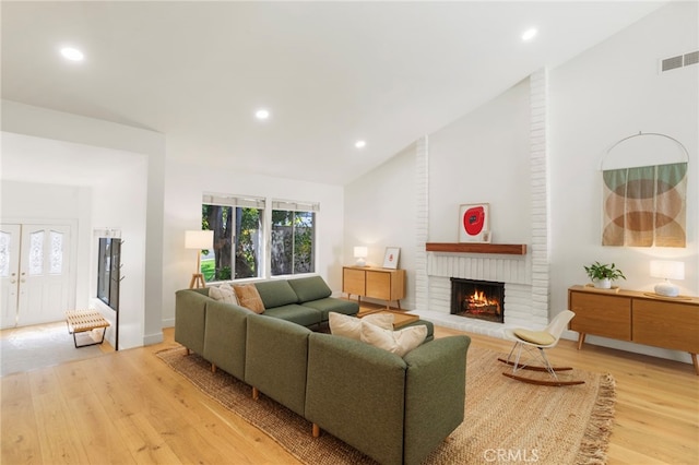 2173 Ranchwood Pl, Riverside, CA 92506 - living room featuring light wood-style flooring, lofted ceiling, a brick fireplace, recessed lighting, and french doors