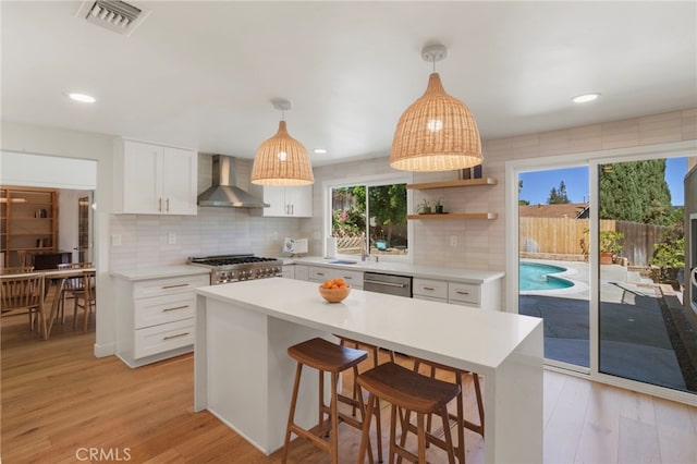 2173 Ranchwood Pl, Riverside, CA 92506 - kitchen featuring wall chimney exhaust hood, dishwasher, tasteful backsplash, white cabinetry, and light wood-style flooring