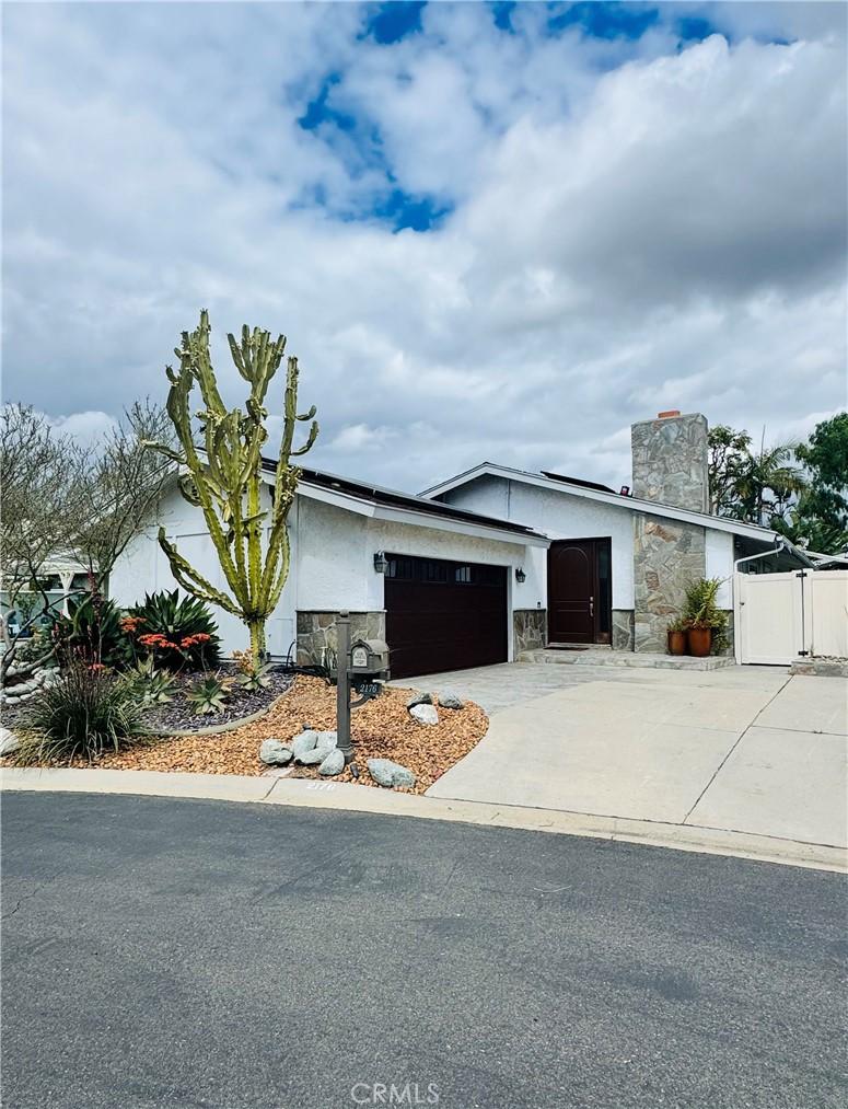 view of front of house with concrete driveway, stone siding, a gate, a chimney, and an attached garage