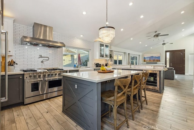 2176 N Pami Cir, Orange, CA 92867 - kitchen featuring wall chimney range hood, light wood-style floors, beverage cooler, range with two ovens, and tasteful backsplash