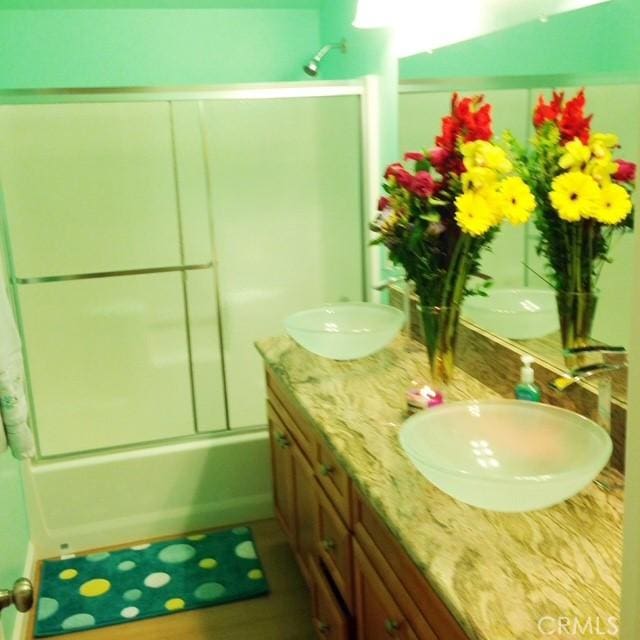 bathroom featuring a sink, double vanity, and shower / bath combination with glass door