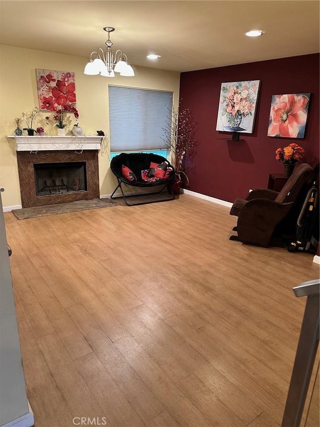 sitting room featuring wood finished floors, recessed lighting, a notable chandelier, and a premium fireplace