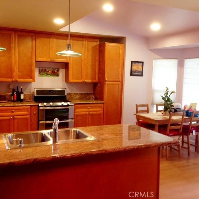 kitchen with recessed lighting, light wood-style floors, a sink, range with two ovens, and pendant lighting