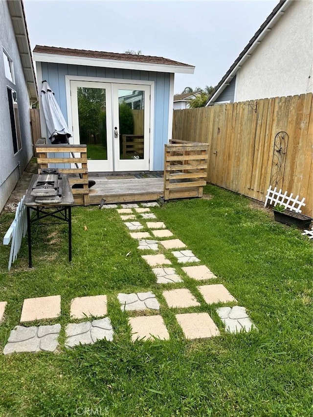 view of yard featuring fence and french doors