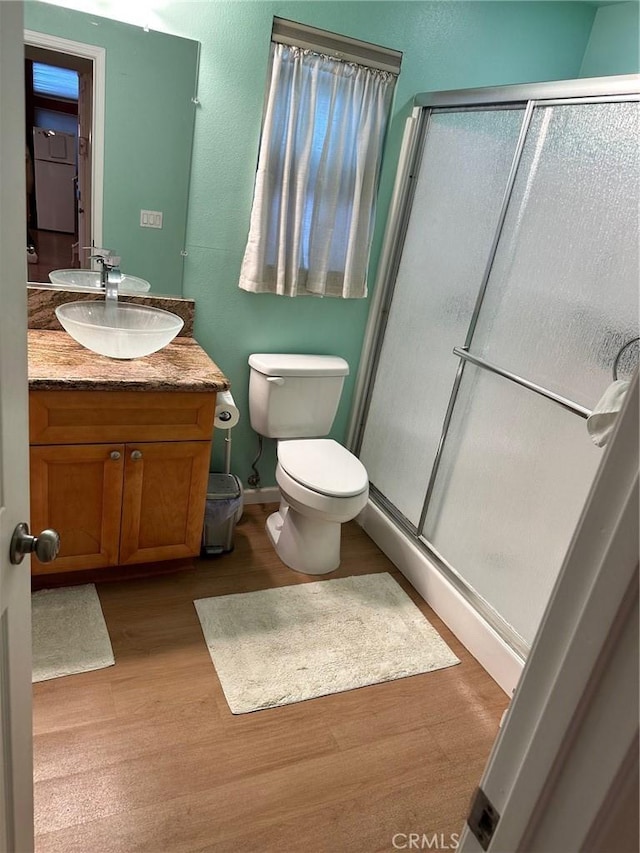 bathroom featuring toilet, wood finished floors, a shower stall, and vanity