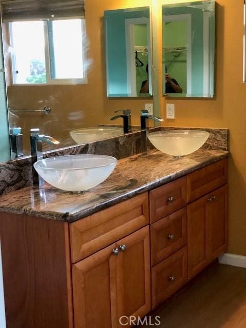 full bath featuring baseboards, double vanity, and a sink