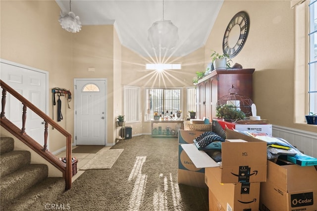 carpeted entryway with a high ceiling, an inviting chandelier, stairway, and plenty of natural light