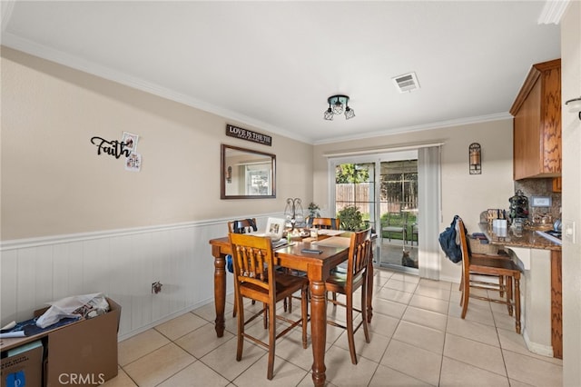 dining space with ornamental molding, visible vents, wainscoting, and light tile patterned floors