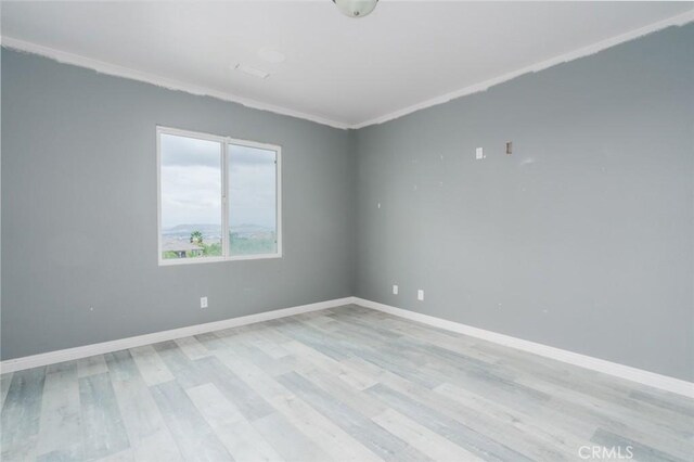 1059 Stowell Ranch Cir, Corona, CA 92881 - spare room featuring light wood-style floors, crown molding, and baseboards