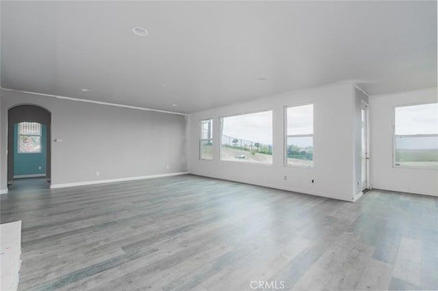 1059 Stowell Ranch Cir, Corona, CA 92881 - unfurnished living room with arched walkways, wood finished floors, and baseboards