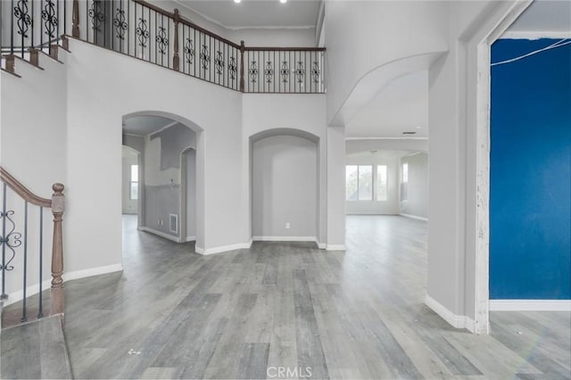 1059 Stowell Ranch Cir, Corona, CA 92881 - foyer featuring stairs, baseboards, arched walkways, wood finished floors, and a high ceiling