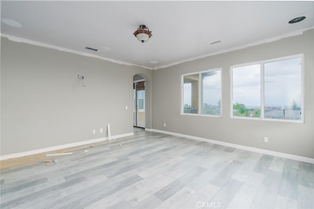 1059 Stowell Ranch Cir, Corona, CA 92881 - spare room featuring baseboards, arched walkways, crown molding, and light wood-style flooring