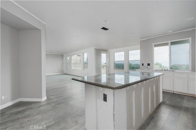 1059 Stowell Ranch Cir, Corona, CA 92881 - kitchen with white cabinets, a healthy amount of sunlight, light wood finished floors, and a center island