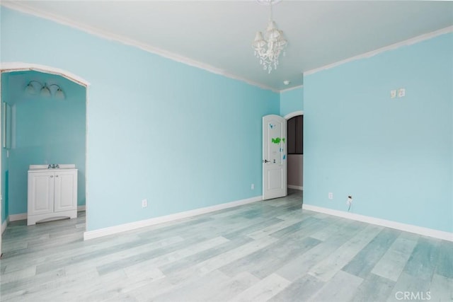 1059 Stowell Ranch Cir, Corona, CA 92881 - spare room featuring crown molding, baseboards, an inviting chandelier, arched walkways, and light wood-type flooring