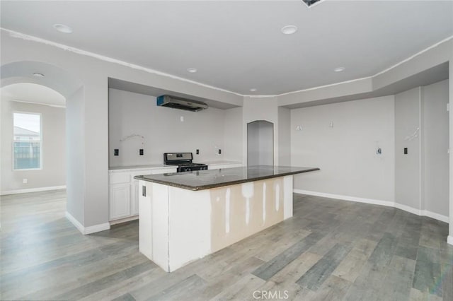 1059 Stowell Ranch Cir, Corona, CA 92881 - kitchen with light wood-style flooring, stainless steel gas stove, baseboards, arched walkways, and white cabinets