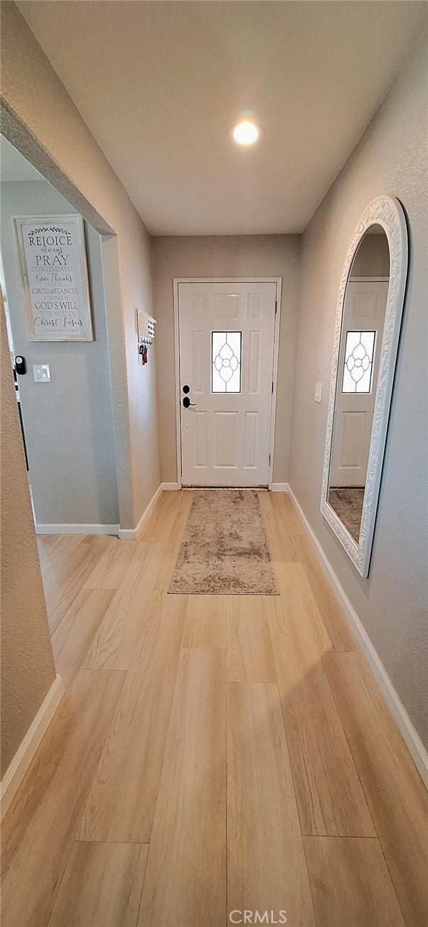 foyer with light wood-style flooring and baseboards